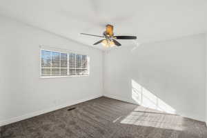 Carpeted empty room with ceiling fan and lofted ceiling