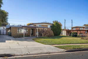 Traditional-style home featuring driveway, a storage shed, brick siding, and a carport