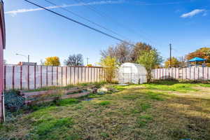 Fenced backyard with an outbuilding, an exterior structure, and a garden