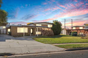 Traditional home featuring concrete driveway, a lawn, brick siding, and a storage unit