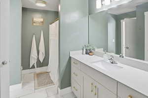 Bathroom featuring curtained shower, vanity, and light marble finish floors