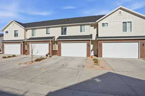 View of front of property featuring board and batten siding, concrete driveway, a garage, and brick siding