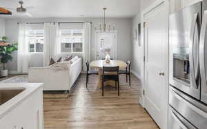 Dining area featuring light wood finished floors, a chandelier, and a ceiling fan