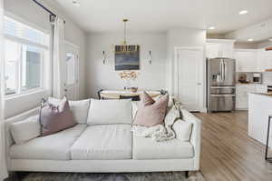 Living room featuring light wood-style floors, recessed lighting, and a chandelier