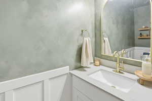 Bathroom featuring vanity, a wainscoted wall, and a decorative wall