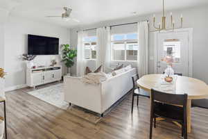 Living area featuring light wood-style floors, a chandelier, and ceiling fan