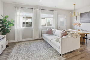 Living area featuring light wood finished floors, a chandelier, and a ceiling fan