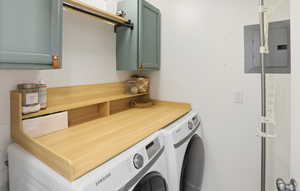 Laundry room with electric panel, washer and dryer, and cabinet space