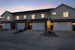 View of front of house with board and batten siding, concrete driveway, and brick siding