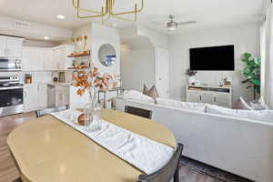 Dining space with a chandelier, dark wood-style floors, ceiling fan, and recessed lighting