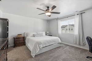 Bedroom with light colored carpet, ceiling fan, and a textured ceiling