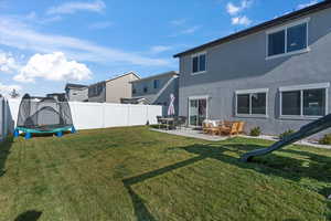Fenced backyard with a trampoline, a patio area, and a residential view