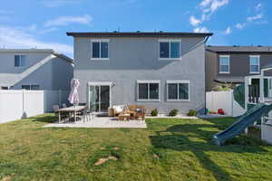 Rear view of property featuring a patio area, a fenced backyard, a playground, and stucco siding