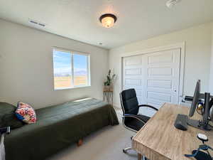 Bedroom featuring a textured ceiling, a closet, carpet, and a desk