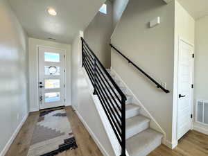 Foyer entrance with light wood finished floors, a textured ceiling, stairway, and recessed lighting