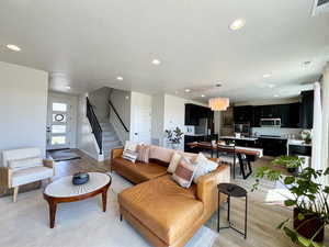 Living room featuring light wood-style flooring, recessed lighting, stairway, a textured ceiling, and a chandelier