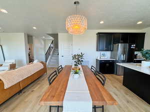 Dining space with recessed lighting, a chandelier, a textured ceiling, stairway, and light wood-style floors