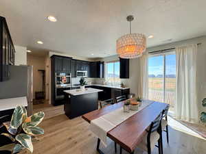 Dining area featuring light wood finished floors, plenty of natural light, recessed lighting, a textured ceiling, and a chandelier