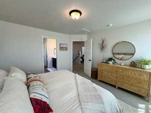 Carpeted bedroom with a textured ceiling and ensuite bathroom