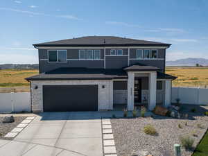 Prairie-style house with stone siding, an attached garage, concrete driveway, roof with shingles, and a mountain view