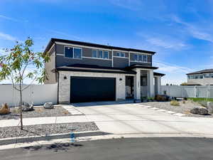 View of front of property with stone siding, a gate, solar panels, concrete driveway, and a garage