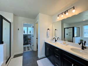 Full bathroom featuring a textured ceiling, a shower stall, double vanity, and a walk in closet