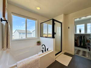 Bathroom with a textured ceiling, a stall shower, a garden tub, and dark tile patterned flooring