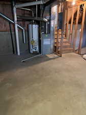 Unfinished below grade area featuring gas water heater, heating unit, and electric panel