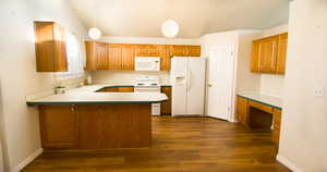 Kitchen featuring white appliances, decorative light fixtures, light countertops, and brown cabinets