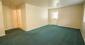 Empty room with baseboards and dark colored carpet