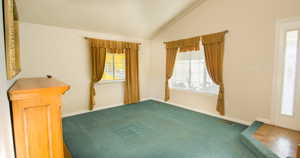 Carpeted spare room with vaulted ceiling and baseboards