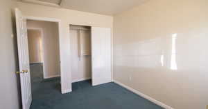 Unfurnished bedroom with dark carpet and a closet