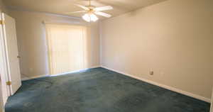 Empty room with dark carpet and a ceiling fan