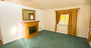 Unfurnished living room with a glass covered fireplace and carpet flooring