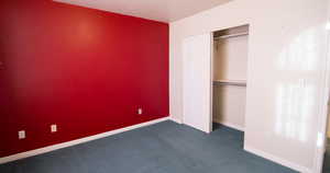 Unfurnished bedroom with dark carpet and a closet