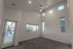 Empty room with dark carpet, a high ceiling, ceiling fan, and recessed lighting