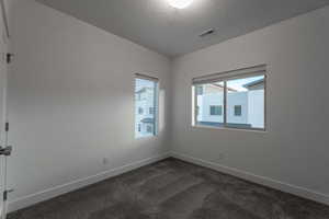 Unfurnished room with dark carpet and a textured ceiling