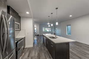 Kitchen featuring dark brown cabinets, appliances with stainless steel finishes, dark wood-style floors, and recessed lighting