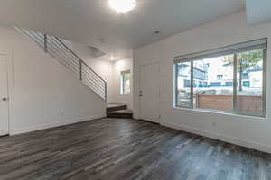 Entryway with stairs, dark wood-type flooring, and a textured ceiling
