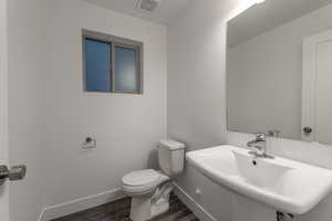 Half bathroom with baseboards and dark wood-type flooring