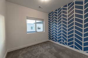 Empty room with a textured ceiling and carpet floors