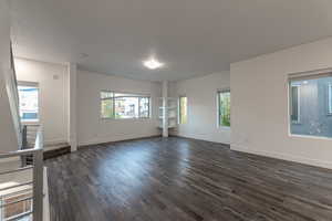 Unfurnished living room with healthy amount of natural light and dark wood-style flooring