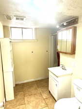 Bathroom with vanity, a textured ceiling, curtained shower, and light tile patterned floors