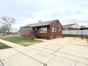 View of front of property featuring brick siding, a chimney, and concrete driveway