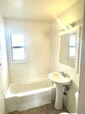Bathroom featuring a bath, a textured ceiling, and tile patterned flooring