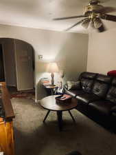 Carpeted living room with arched walkways and ceiling fan. APT 2