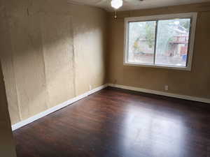 Unfurnished room with dark wood-style flooring and ceiling fan. APT 3