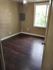 Spare room featuring dark wood-style flooring and electric panel. APT 3