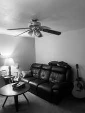 Living area with a ceiling fan and carpet flooring. APT 2