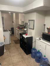 Kitchen featuring a textured wall, white gas range oven, light tile patterned floors, > APT 2stainless steel microwave, and white cabinets